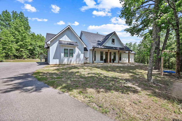 modern farmhouse style home featuring a porch, a shingled roof, and board and batten siding