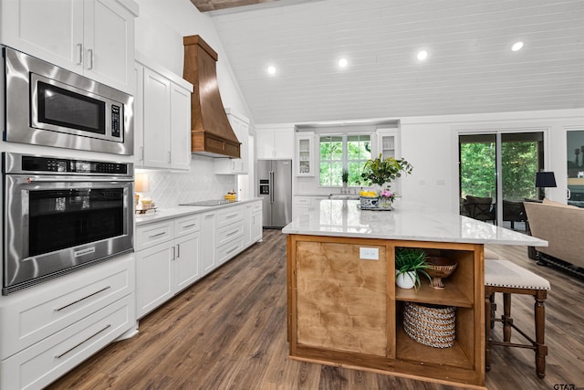 kitchen with lofted ceiling, decorative backsplash, stainless steel appliances, a center island, and a kitchen bar