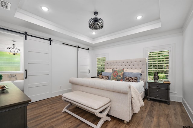 bedroom featuring dark wood finished floors, a raised ceiling, a barn door, and visible vents