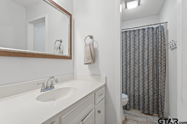 bathroom with vanity, toilet, and a textured ceiling