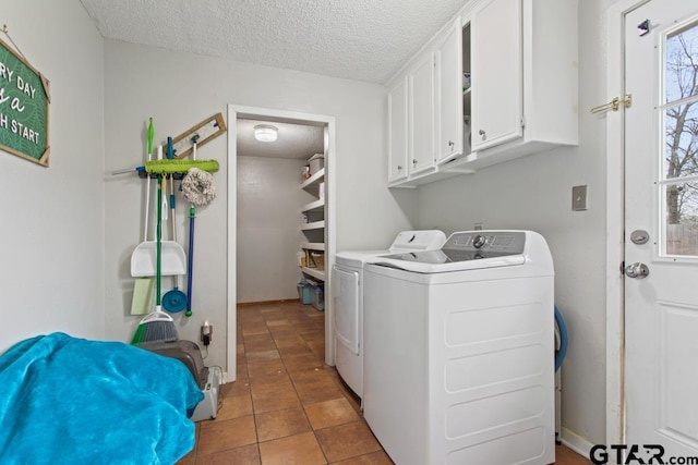 clothes washing area with washer and clothes dryer, tile patterned floors, cabinets, and a textured ceiling