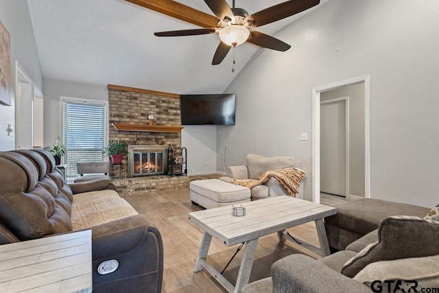 living room featuring ceiling fan, a brick fireplace, high vaulted ceiling, and light hardwood / wood-style floors