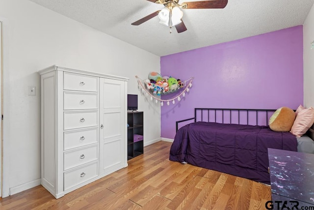 bedroom with ceiling fan, light hardwood / wood-style floors, and a textured ceiling