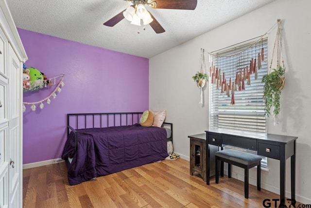 bedroom with ceiling fan, light hardwood / wood-style flooring, and a textured ceiling