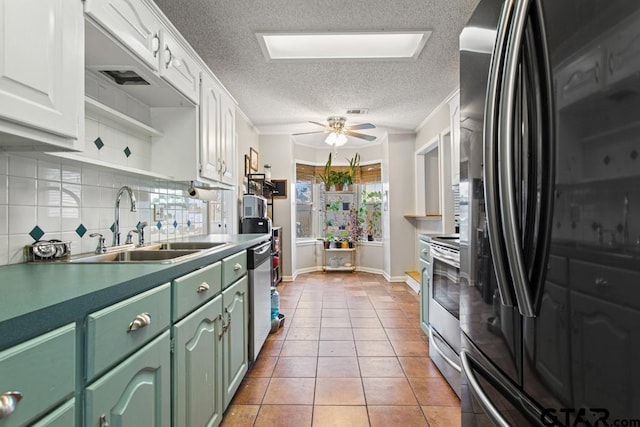 kitchen with light tile patterned flooring, sink, white cabinetry, appliances with stainless steel finishes, and backsplash