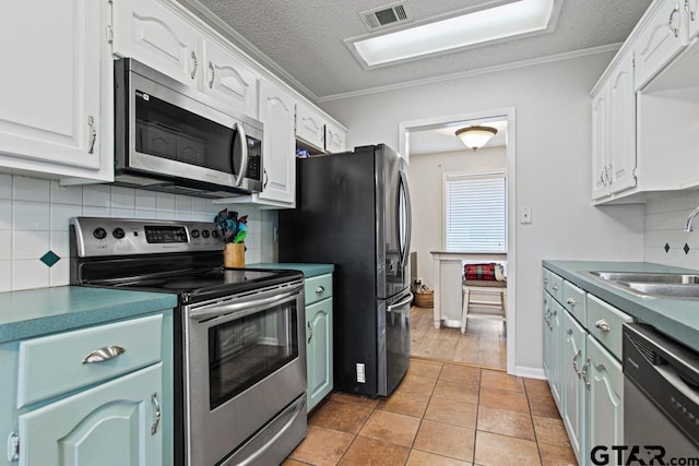 kitchen with white cabinetry, stainless steel appliances, light tile patterned flooring, and sink