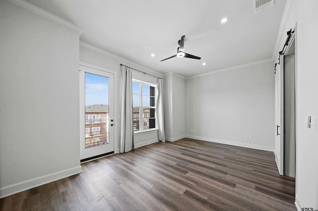 empty room with ornamental molding, ceiling fan, a barn door, and dark hardwood / wood-style floors