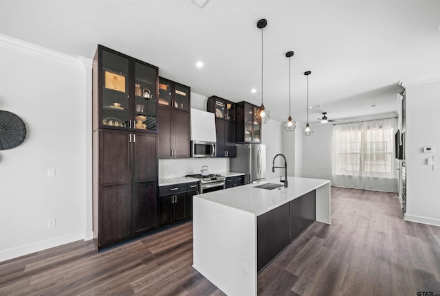 kitchen with a center island with sink, crown molding, appliances with stainless steel finishes, dark hardwood / wood-style floors, and hanging light fixtures