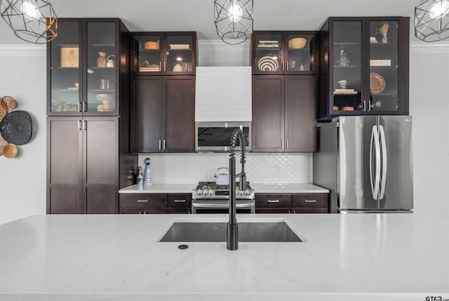 kitchen featuring ornamental molding, backsplash, appliances with stainless steel finishes, decorative light fixtures, and dark brown cabinetry