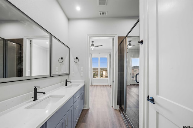 bathroom featuring vanity, hardwood / wood-style floors, a shower with door, and ceiling fan