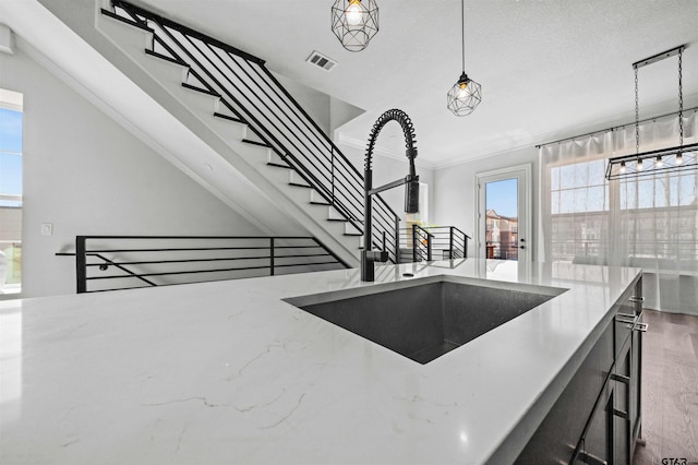 kitchen with dark wood-type flooring, sink, decorative light fixtures, and light stone countertops