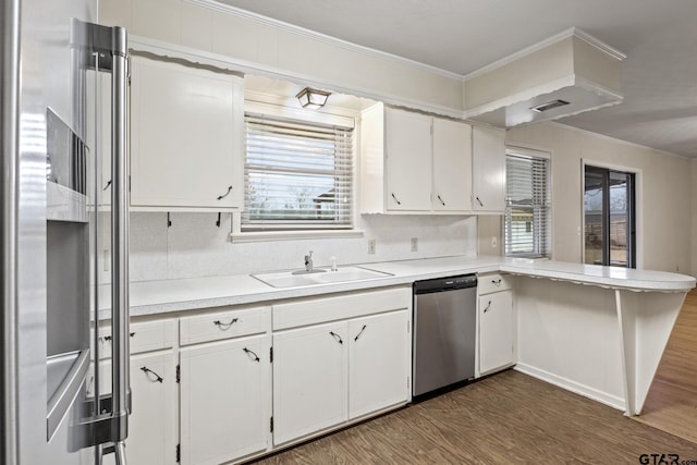 kitchen featuring crown molding, appliances with stainless steel finishes, dark hardwood / wood-style flooring, kitchen peninsula, and white cabinets