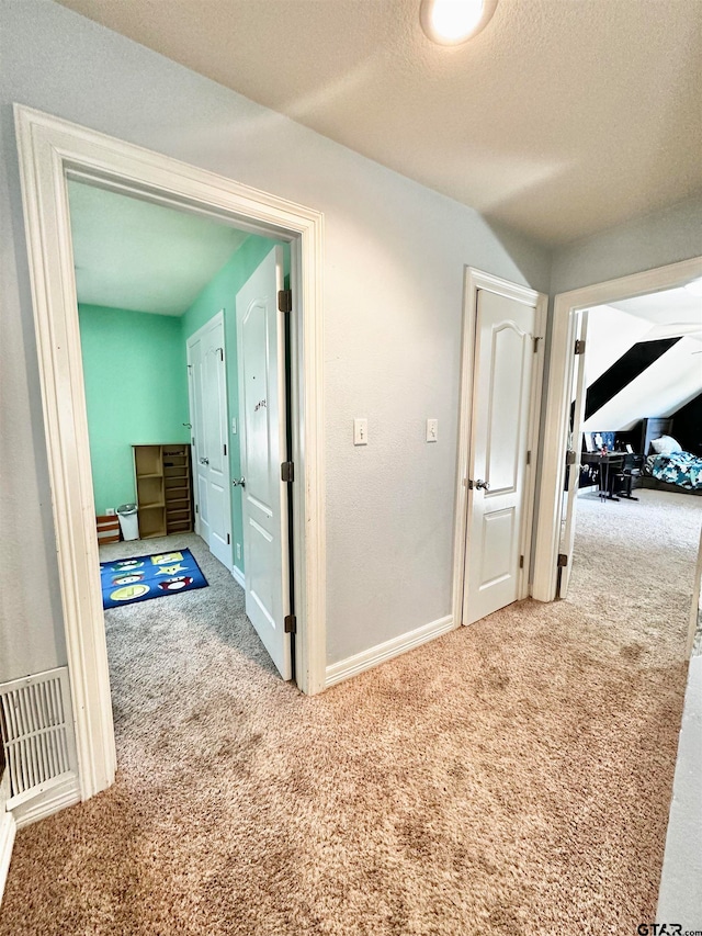 corridor with carpet floors and a textured ceiling