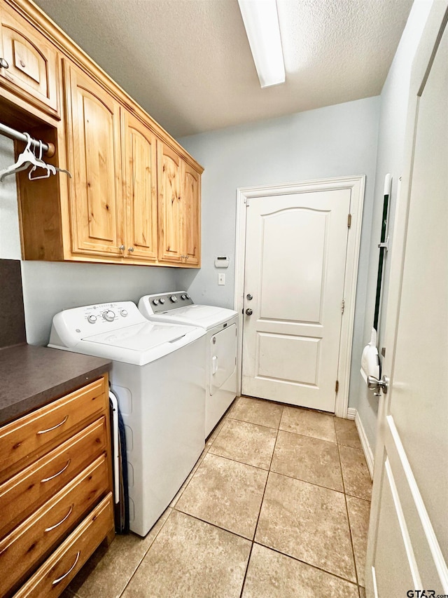 clothes washing area featuring cabinets, independent washer and dryer, a textured ceiling, and light tile patterned floors