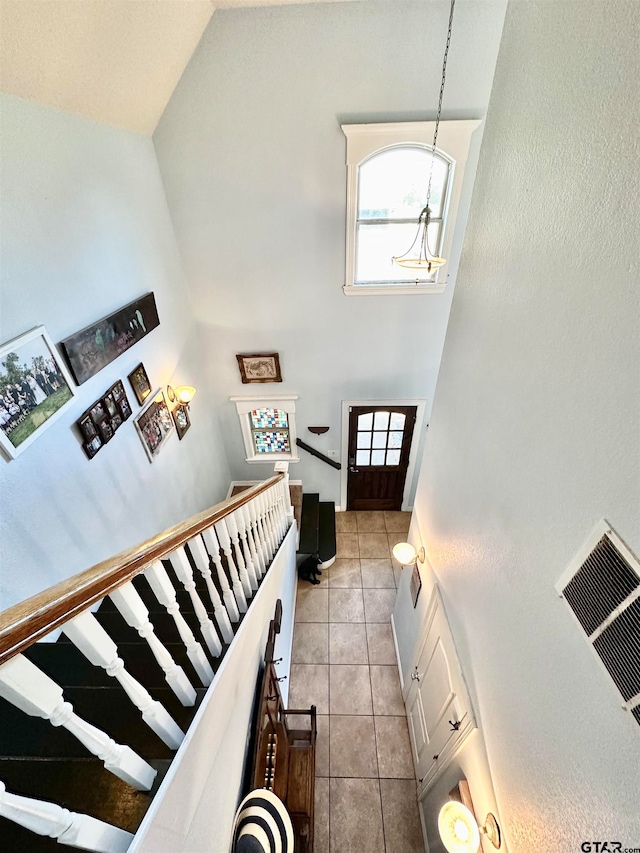 tiled foyer featuring a towering ceiling and an inviting chandelier