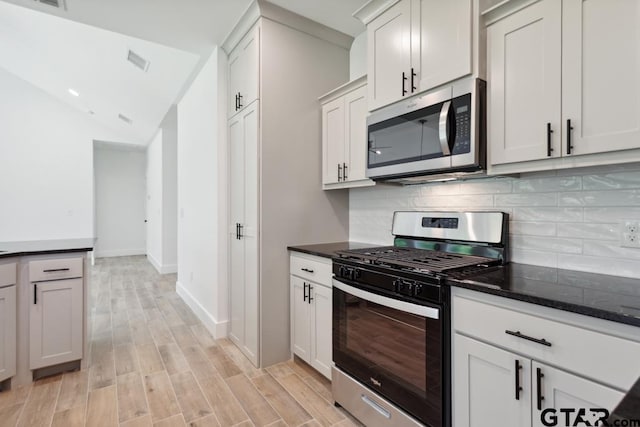 16234 Crossing Cir, Lindale, TX 75771 - kitchen with visible vents, dark stone counters, decorative backsplash, light wood finished floors, and appliances with stainless steel finishes