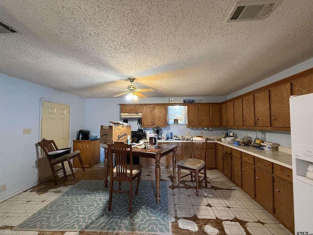 kitchen with ceiling fan, white refrigerator with ice dispenser, and a textured ceiling