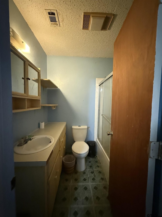 full bathroom featuring toilet, a textured ceiling, tile patterned flooring, shower / bath combination with glass door, and vanity