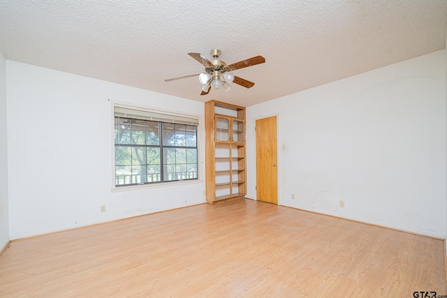 empty room with a textured ceiling, light wood-type flooring, and ceiling fan