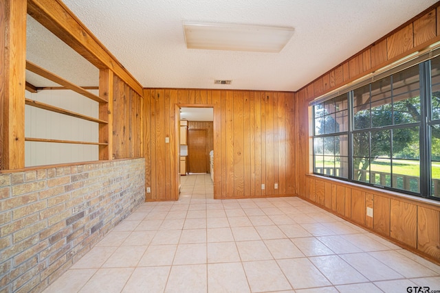 tiled empty room with a textured ceiling and wooden walls