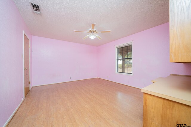 interior space featuring ceiling fan, light hardwood / wood-style floors, and a textured ceiling