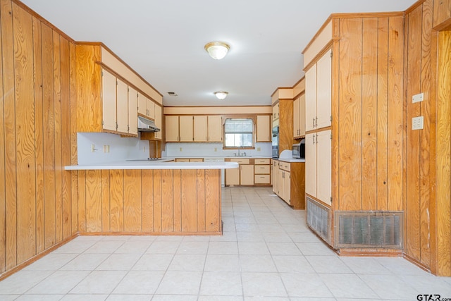 kitchen featuring sink, kitchen peninsula, wood walls, light brown cabinetry, and light tile patterned floors