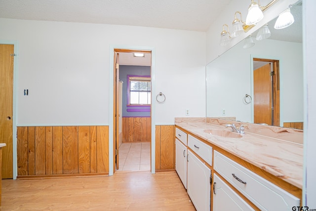 bathroom with hardwood / wood-style flooring, vanity, a textured ceiling, and wooden walls