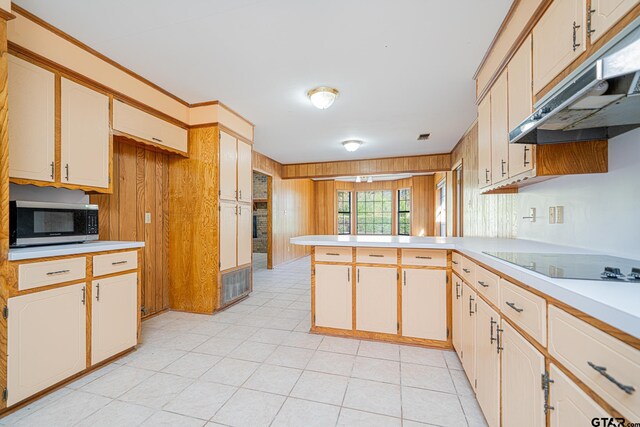 kitchen featuring black electric stovetop, kitchen peninsula, and wooden walls