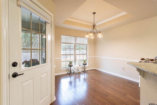 dining area with dark hardwood / wood-style floors, ornamental molding, a raised ceiling, and a chandelier