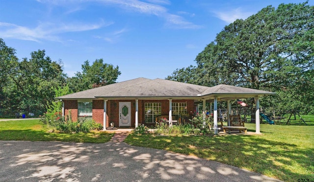 ranch-style home featuring a playground, covered porch, and a front yard