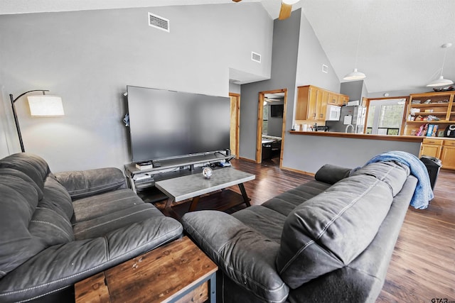 living room featuring high vaulted ceiling, wood finished floors, visible vents, and baseboards