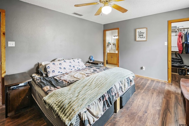 bedroom featuring baseboards, visible vents, wood finished floors, a walk in closet, and a closet