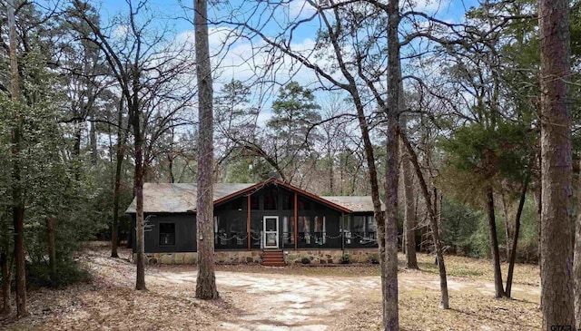 view of front of home featuring a sunroom and dirt driveway