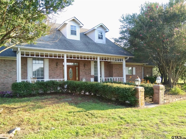 8099 W Interstate Highway 30, Cumby, TX 75433 - cape cod house featuring a front yard, brick siding, a porch, and roof with shingles