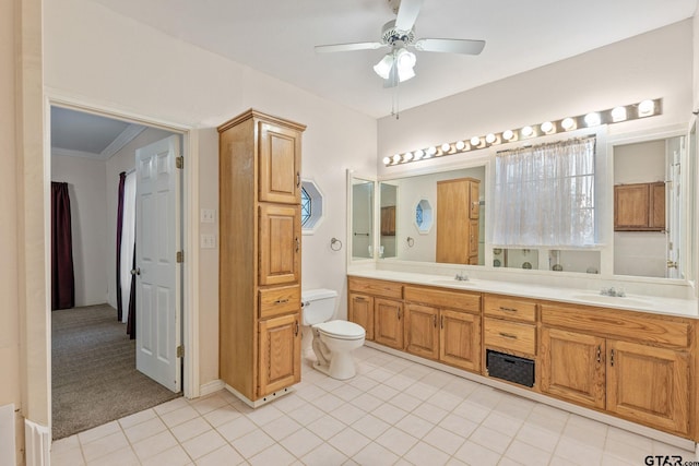 bathroom with tile patterned flooring, ornamental molding, ceiling fan, vanity, and toilet