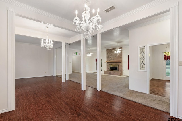 interior space featuring dark wood-type flooring, a notable chandelier, crown molding, and a fireplace