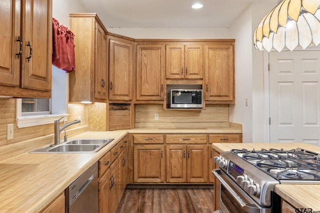 kitchen with dark wood-type flooring, backsplash, sink, and stainless steel appliances