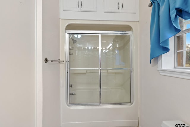 bathroom with shower / bath combination with glass door and toilet