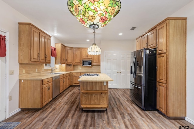 kitchen with dark wood-type flooring, a center island, sink, pendant lighting, and appliances with stainless steel finishes