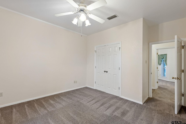 unfurnished bedroom featuring ornamental molding, a closet, ceiling fan, and carpet floors