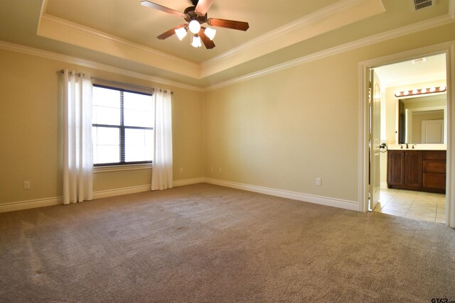 carpeted bedroom featuring a tray ceiling, ceiling fan, crown molding, and ensuite bathroom