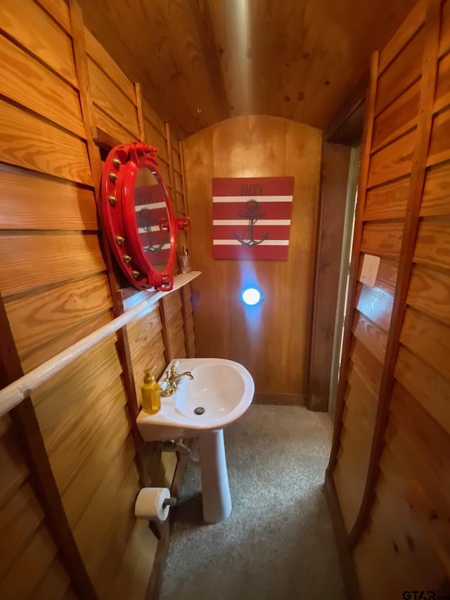 bathroom featuring wood walls, wooden ceiling, sink, and vaulted ceiling