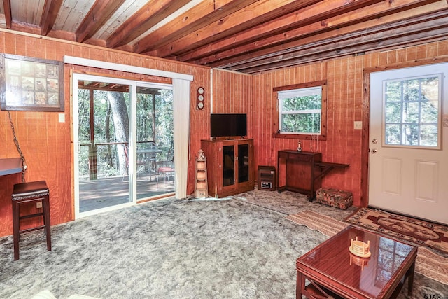 living room with wood ceiling, beam ceiling, carpet floors, and wooden walls