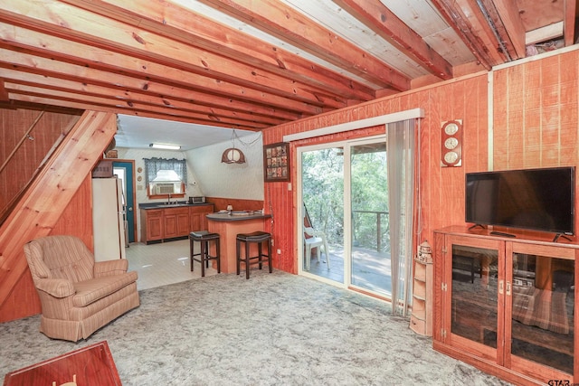 living room with beam ceiling, light colored carpet, and wooden walls