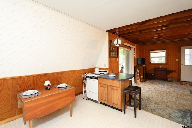 kitchen with white range, kitchen peninsula, a breakfast bar area, and wooden walls