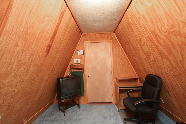 office featuring wood walls, lofted ceiling, and a textured ceiling