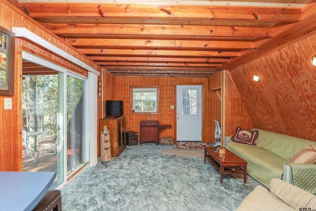 living room with beam ceiling, wood walls, and carpet flooring