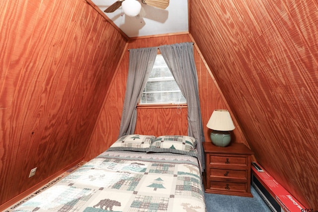 unfurnished bedroom with ceiling fan, wood walls, a baseboard heating unit, and vaulted ceiling