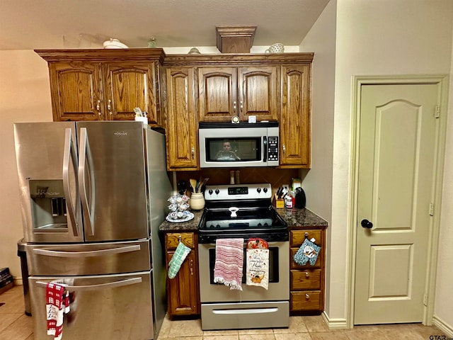 kitchen featuring dark stone countertops, light tile patterned floors, and stainless steel appliances