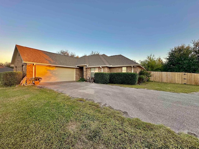 ranch-style home with a garage and a lawn